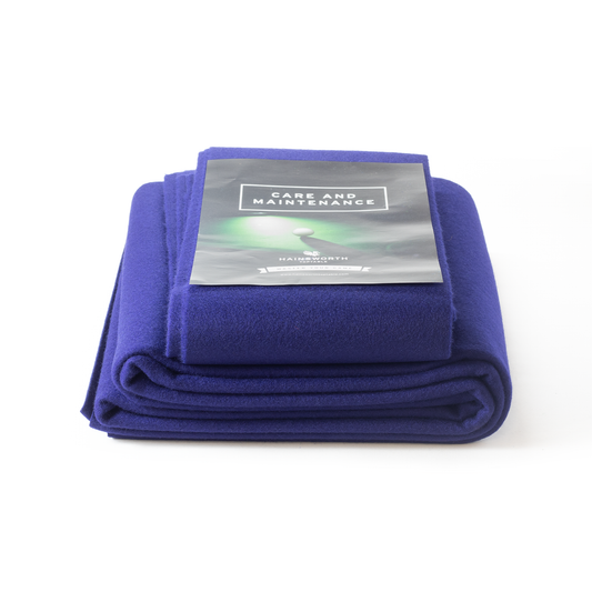 Folded Hainsworth-SMART French Navy pool table cover with a care and maintenance label on a white background