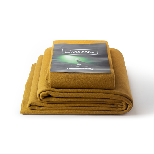 Hainsworth-SMART folded tan coloured pool table cloth with a care and maintenance guide on a white background